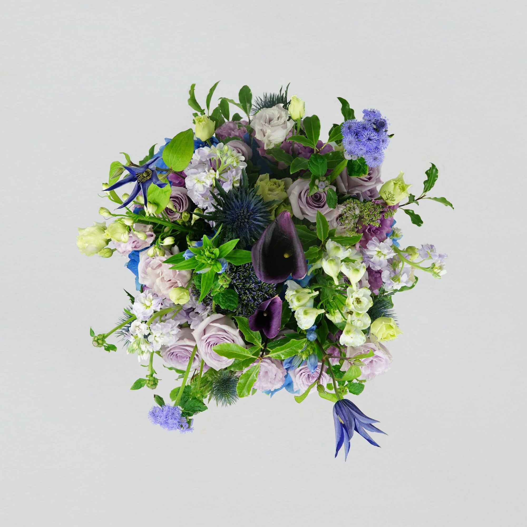 A selection of blue and purple fresh florals arranged in a white round box