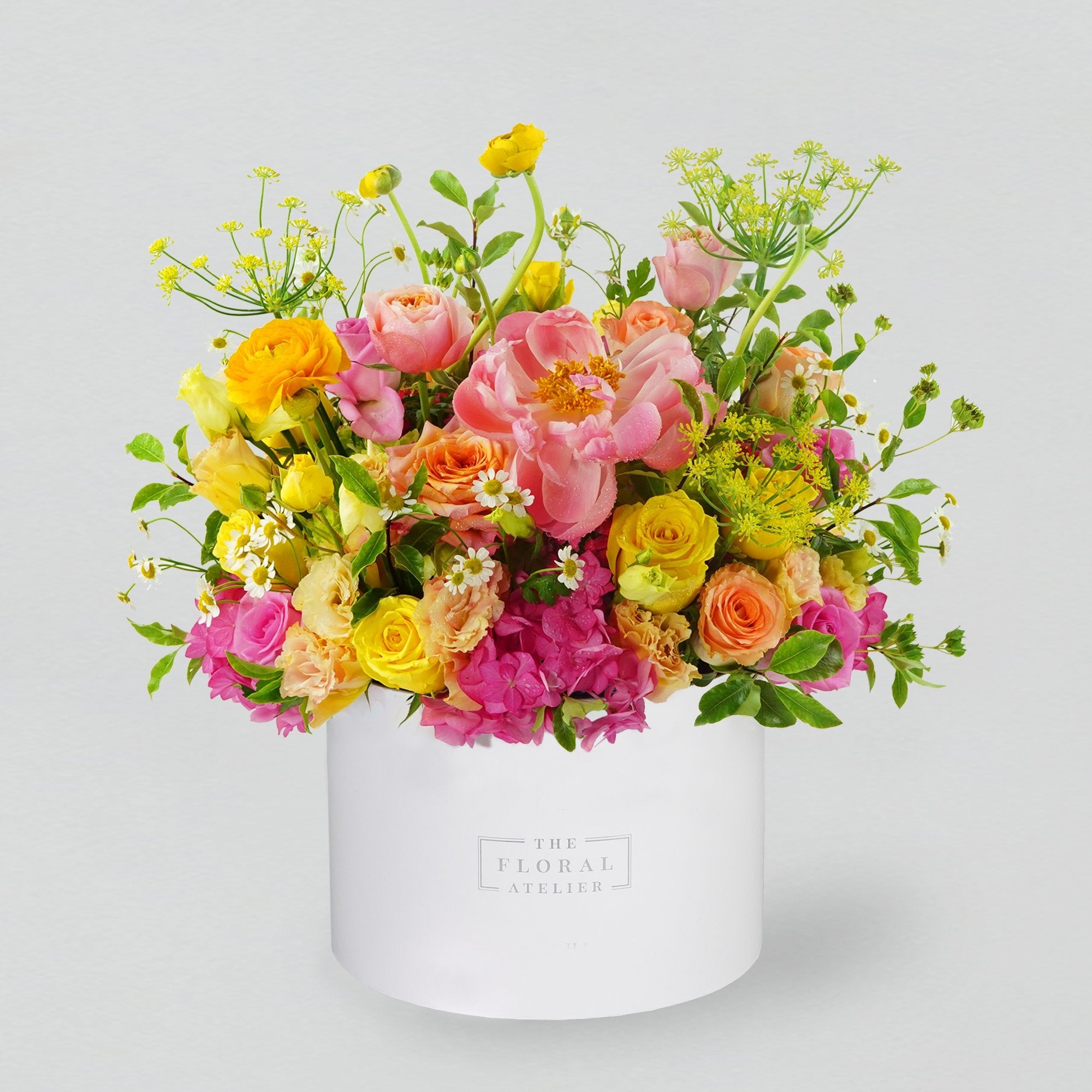 A bright selection of fresh florals arranged in a white round box