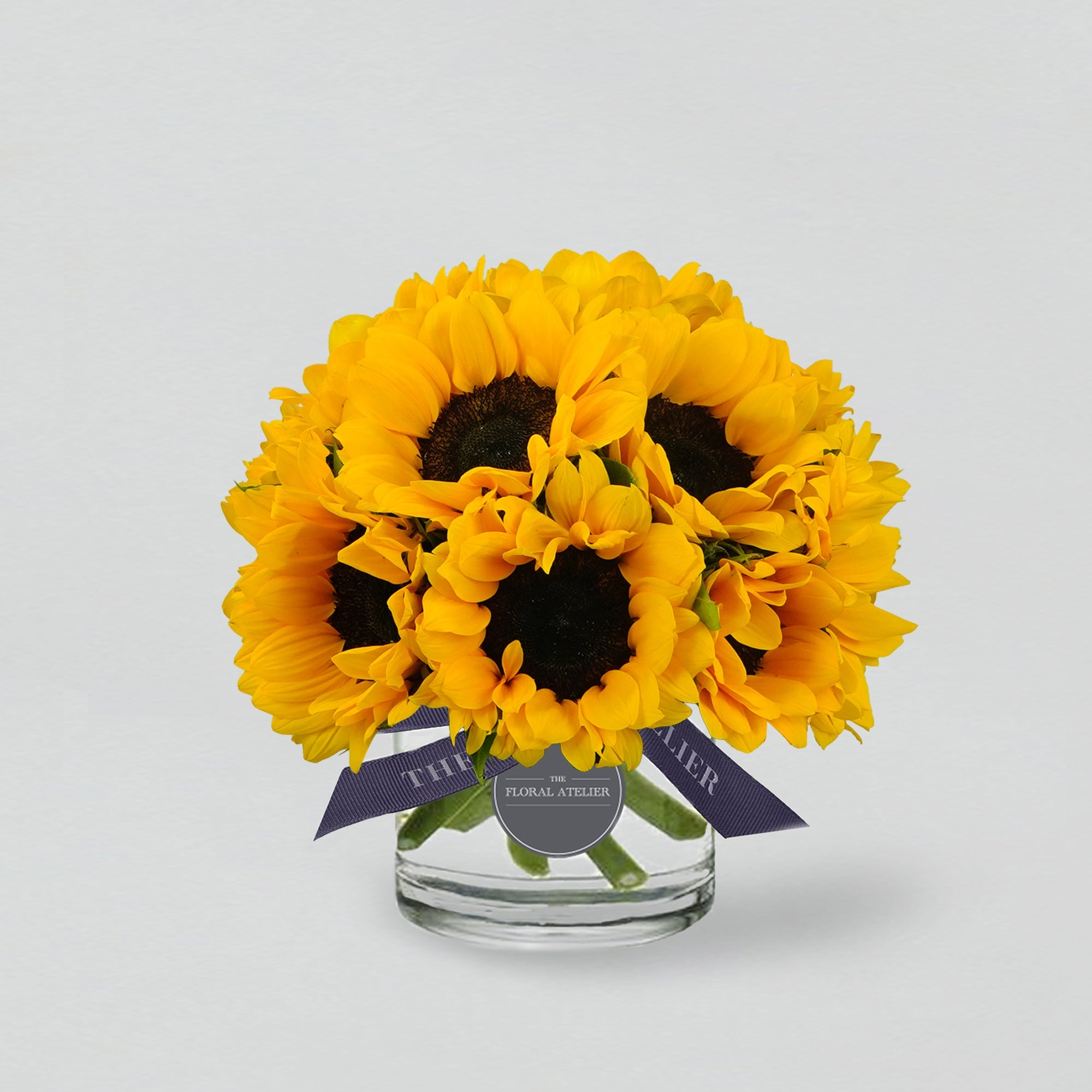 Fresh yellow sunflowers arranged in a clear glass vase